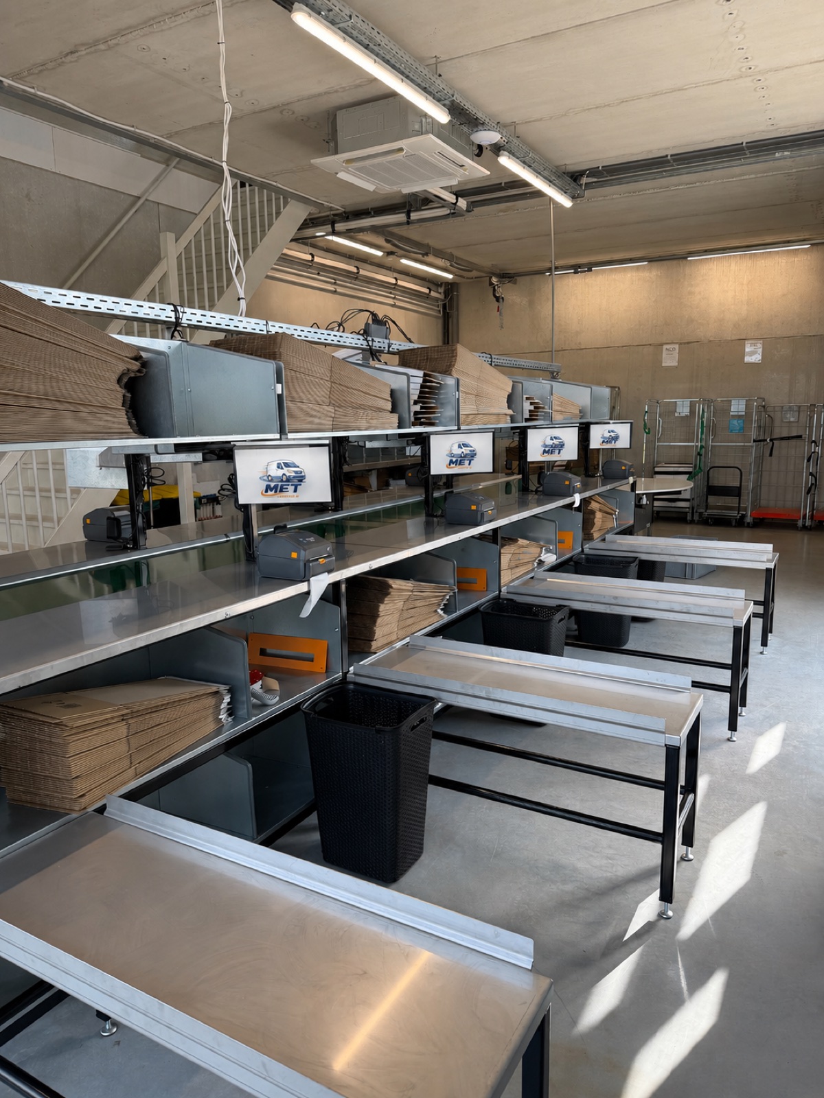 Rij werkstations met voorraad gevouwen dozen en labelprinters